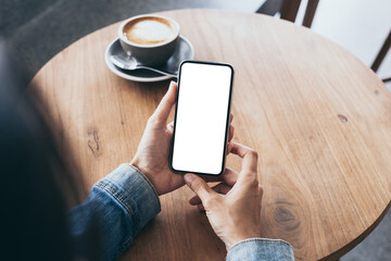 cell phone mockup image blank white screen.woman hand holding texting using mobile on desk at coffee shop.background empty space for advertise.work people contact marketing business,technology