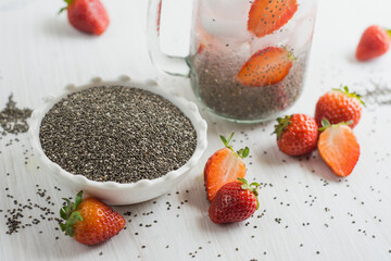Chia seeds bowl and strawberry water water, white background.