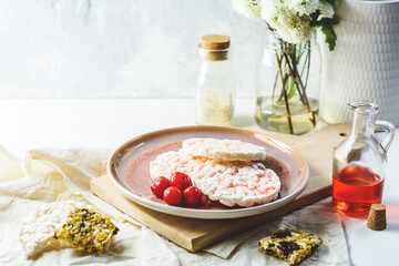 Rice Crackers with Cherry Syrup and Cereal Bar, and some cherries, flowers and white background.