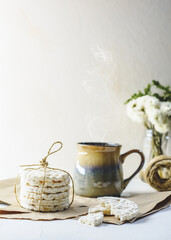 Rice crackers and a cup of tea and some flowers and white background.
