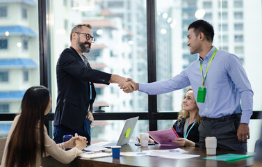 Young manager handshake with new employee. Businessmen making handshake in meeting room, congratulation.