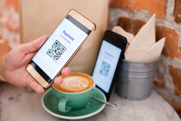 Customer hand using smart phone to scan QR code tag on another smart with coffee in coffee shop or restaurant to accepted generate digital pay without money. Qr code payment concept.