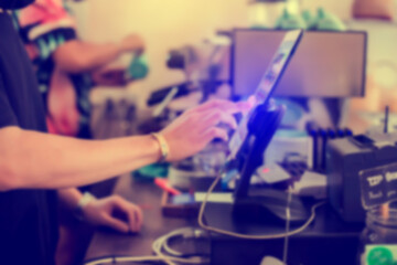 Blurry image of cashier staff using tablet to receive orders from customers at counter service in cafe or store. Cashier takes payment from customer with digital tablet.