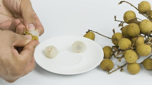 Hand Peel off asia longan fruit on white plate