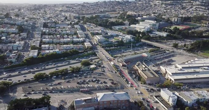 Bart station to Highway traffic during sunset and cars going in opposite direction. Bart train on the track and muni on the road camera move forward