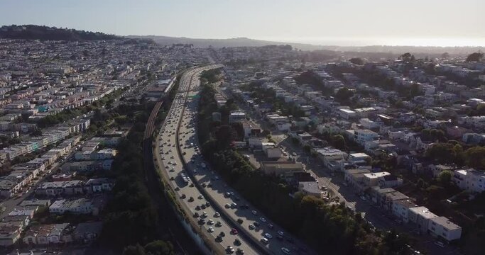 Highway traffic during sunset and cars going in opposite direction. Bart train on the track and muni on the road camera move forward