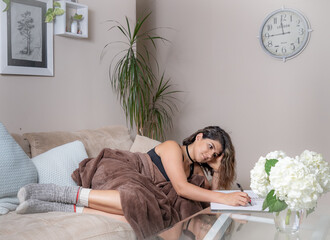 Obraz premium young woman relaxing on sofa while writing in a notebook