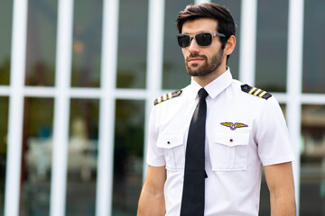 Portrait of helicopter pilot in uniform walk and standing outside with private helicopter background - obrazy, fototapety, plakaty