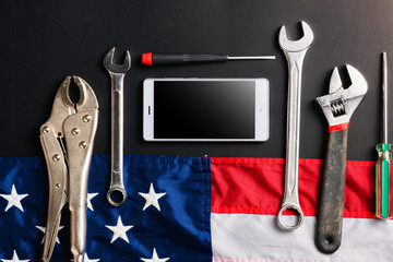 USA Labor day concept, different kinds wrenches, American flag and smartphone blank screen on dark green. First Monday in September, creation labor movement and dedicated to social of American worker