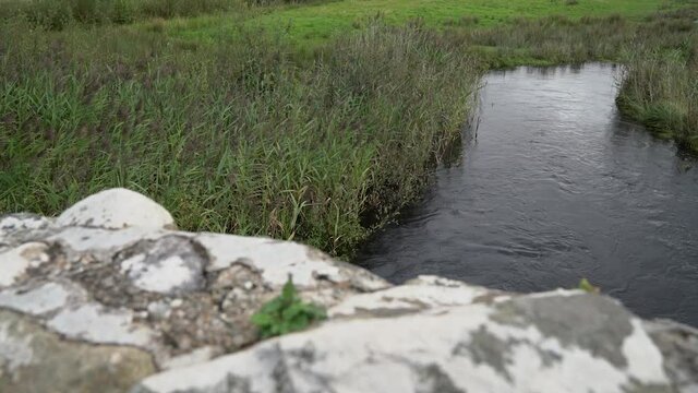 Slow slider shot looking over the east wall of the Quiet Man Bridge (Leam Bridge) with the river in the background.