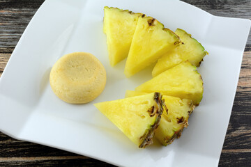 Pineapple shortbread cookie  with pineapple filling and fresh pineapple wedges on white dessert plate