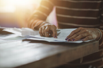 Young woman with papers or bills sitting at old desk table.
