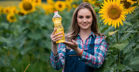 Gorgeous, young, adorable, female farmer holding a bottle of sunflower oil in the middle of a...