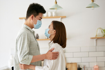 young asian mask wearing couple holding each other