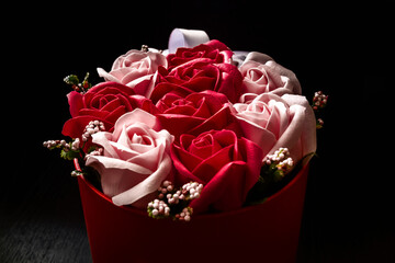A basket with artificial flowers on a dark background close-up.