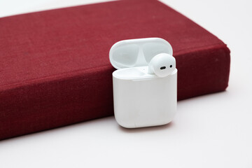 Wireless headphones in an old book with copy space, concept of audiobook, self-study.