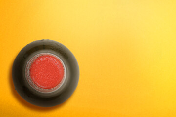 Top view of the beer bottle with a yellow background
