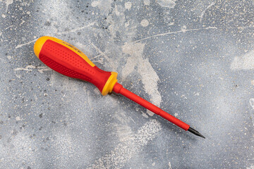 A flat-head screwdriver on a mottled cement surface