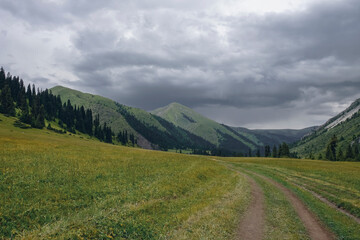 Green mountain valley with clouds. Adventure travel. Outdoor landscape. Summer vacation travel concept. Kazakhstan mountains, Tekes river valley. Tourism in Kazakhstan concept.