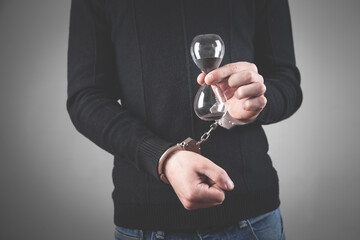 Man with handcuffs holding hourglass.