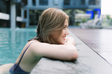 Asian girl on holidays with a perfect white smile bathing in a pool on vacations.