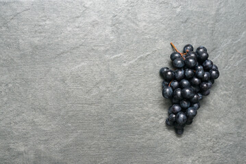 Bunch of black grapes on stone surface flat lay background with copy space.