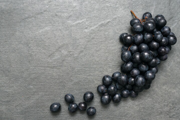 Bunch of black grapes on stone surface flat lay background with copy space.