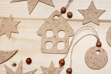 Cardboard decorative stars, small houses and a crescent moon. Handmade Christmas decorations laid out on a wooden background.