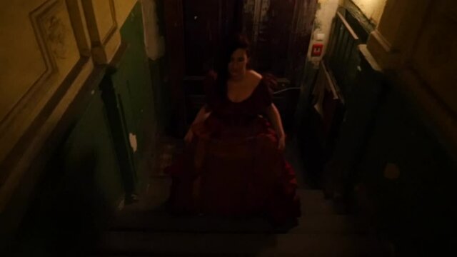 Woman in a red ball dress walking on a dark, vintage, old Starcase. Corridor. Slow Motion