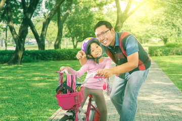 Father accompanying his cycled daughter at park