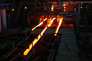 Red hot steel metal billets after molten steel casting.  Continuous casting machine. Background of...