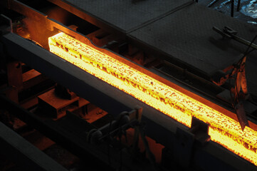 Red hot steel metal billets after molten steel casting.  Continuous casting machine. Background of...