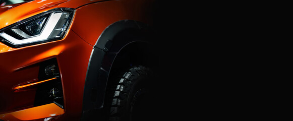 Close up detail on one of the LED headlights orange Pickup Truck on black background free space on right side for text. © I Viewfinder