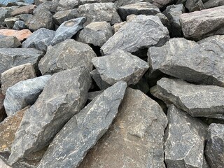 Background texture: many large stones of different shapes. A pile of granite boulders. Concept - stone, hardness, foundation