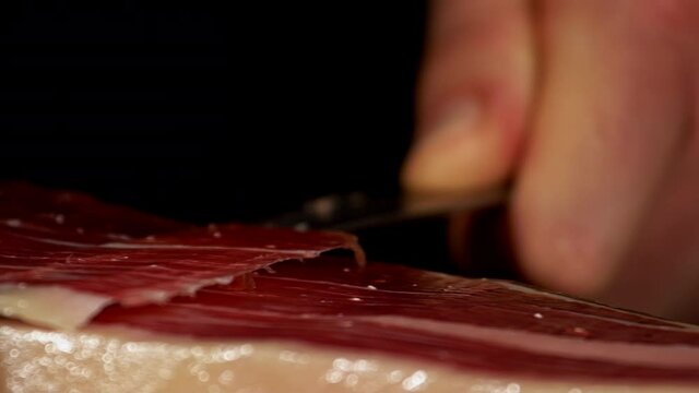 Extra detailed image of a ham cutter with his knife cutting a thin slice of Iberico jamon, short-waisted image. very appetizing the public eager to feed on this delicacy shoot