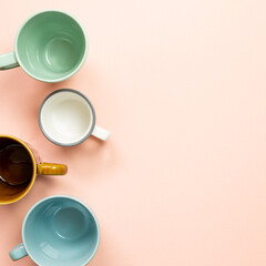 Colorful empty mug cups on pink background. top view