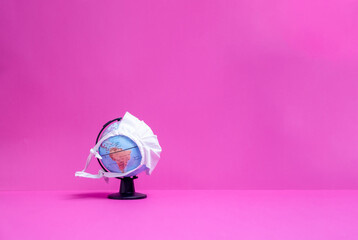 Weltkugel mit weißer Maske mit Sicht auf Amerika mit pinkem Hintergrund
