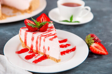 Sweet breakfast, tea and delicious cheesecake with fresh strawberries and mint, homemade recipe without baking, on dark blue stone table. Copy space.