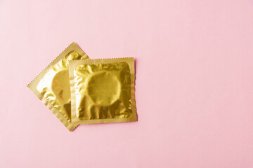 World sexual health or Aids day, Top view flat lay condom in wrapper pack, studio shot isolated on a pink background, Safe sex and reproductive health concept