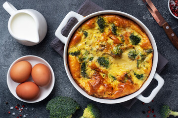 Baked omelet with broccoli in a ceramic dish. Dark concrete table. Healthy diet food dish.