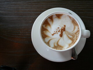coffee with milk in white cup on wooden table in cafe.