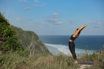 Fototapeta premium Young woman doing yoga outdoors with amazing back view. Bali. Indonesia.