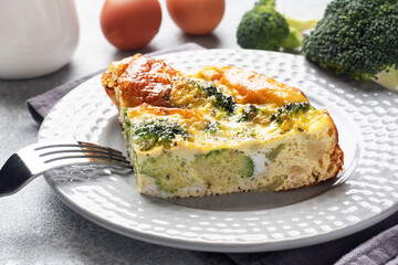 Piece Baked omelet with broccoli on a plate. Concrete table. Healthy diet food dish.