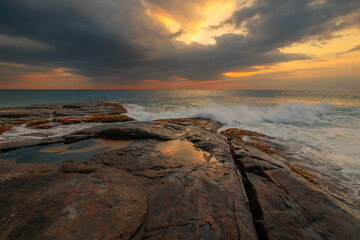 Rocks and stones at the ocean coast under a beautiful sunset sky with clouds on Sri Lanka island.