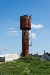 Old rusty water tower on blue sky background