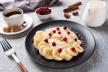 Oatmeal with milk with banana cranberries and sesame seeds. A Cup of coffee, healthy Breakfast Concept.