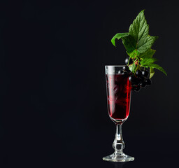 Glass of blackcurrant liqueur or syrup with leaves and berries.
