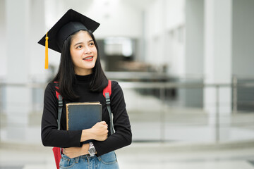 Portrait of female teenager college student holding books with school backpack and wearing graduation hat represent graduation concept.