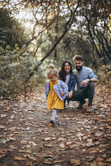 happy young family: stylish father, beautiful mom and sweet little daughter spend a day together, child running in nature at sunset. selective focus, noise effect