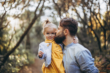 young, stylish bearded father walking with his little daughter in nature at sunset. Family photos...